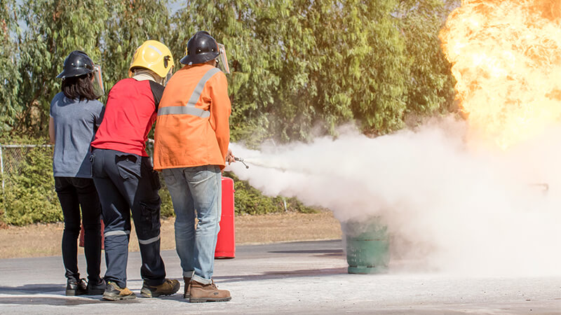 three people training for fire similation with fire extinguisher